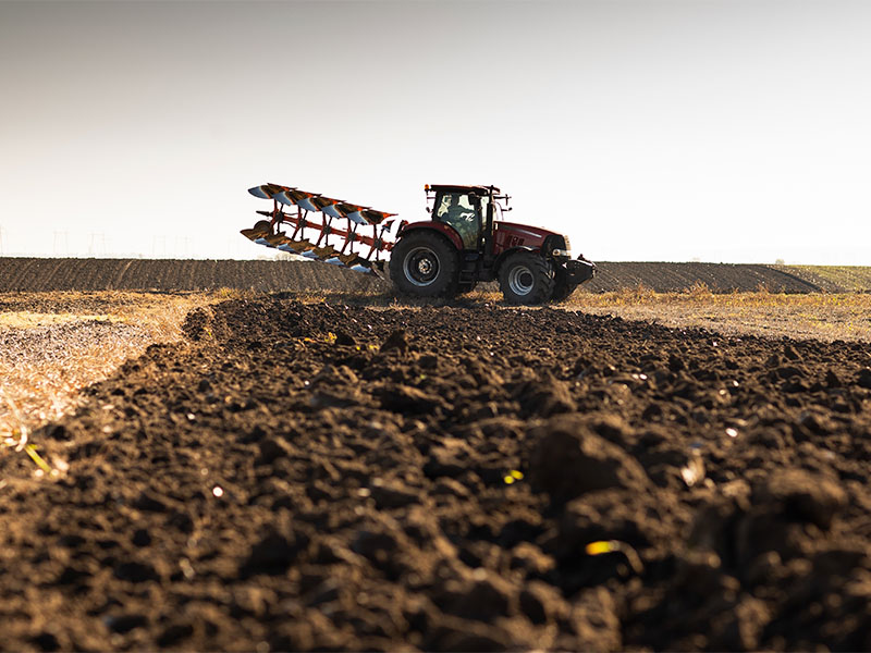 Traktori aloittamassa kev&auml;&auml;n peltoty&ouml;t maanmuokkauksessa pellolla
